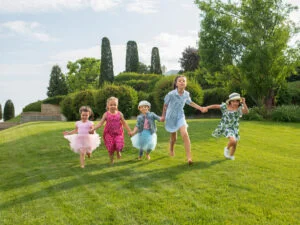 "Group of joyful children running on a grassy lawn in a garden."